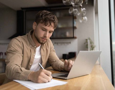 Young man writing an expository essay at his desk